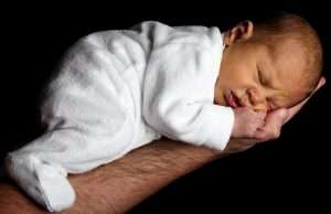 Neugeborenes schläft friedlich auf einer Männerhand